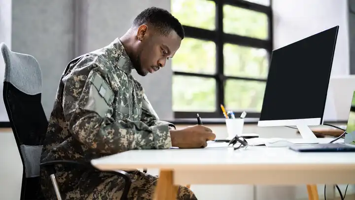 veteran in fatigues filling out paperwork at desk