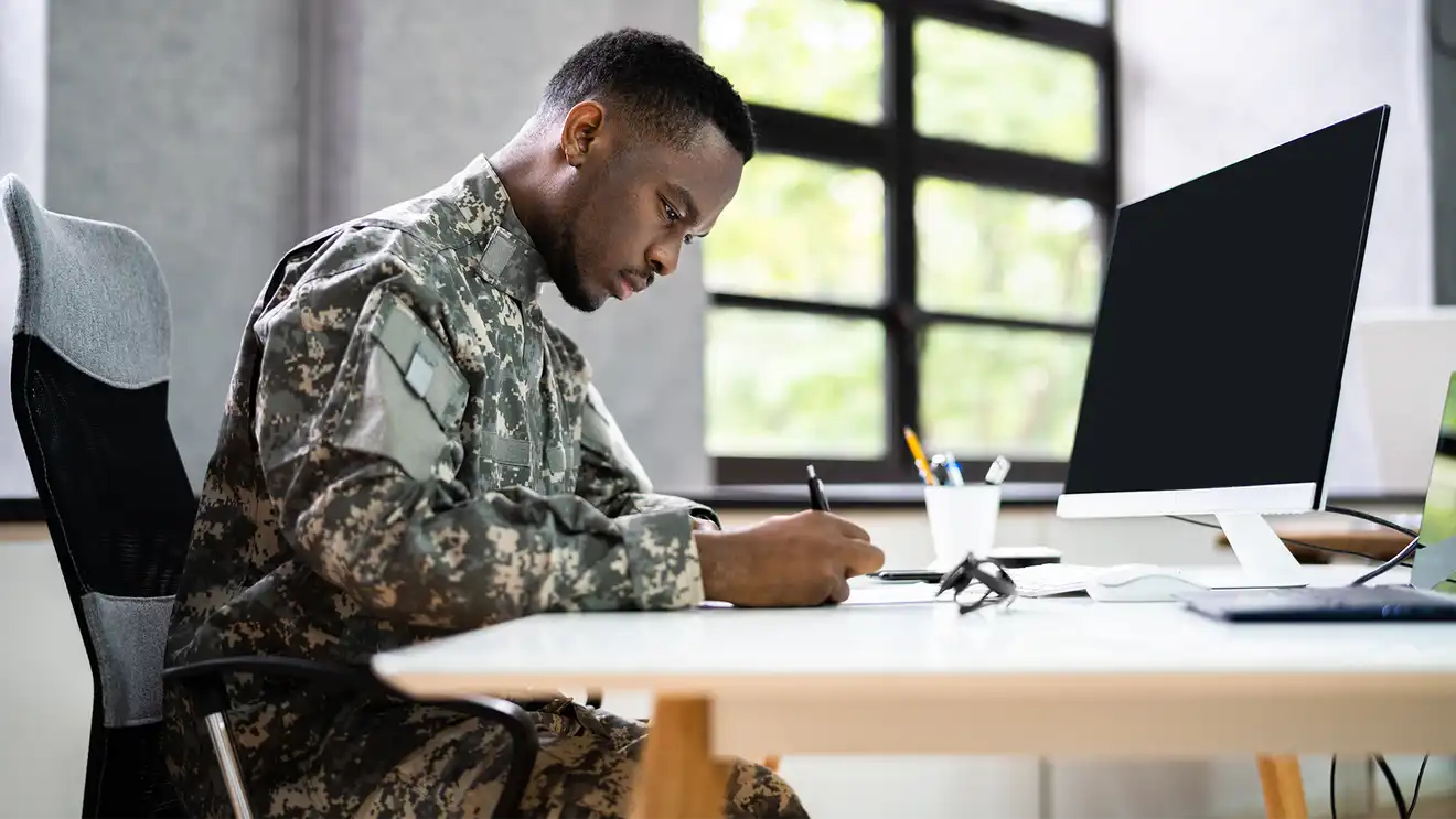 veteran in fatigues filling out paperwork at desk